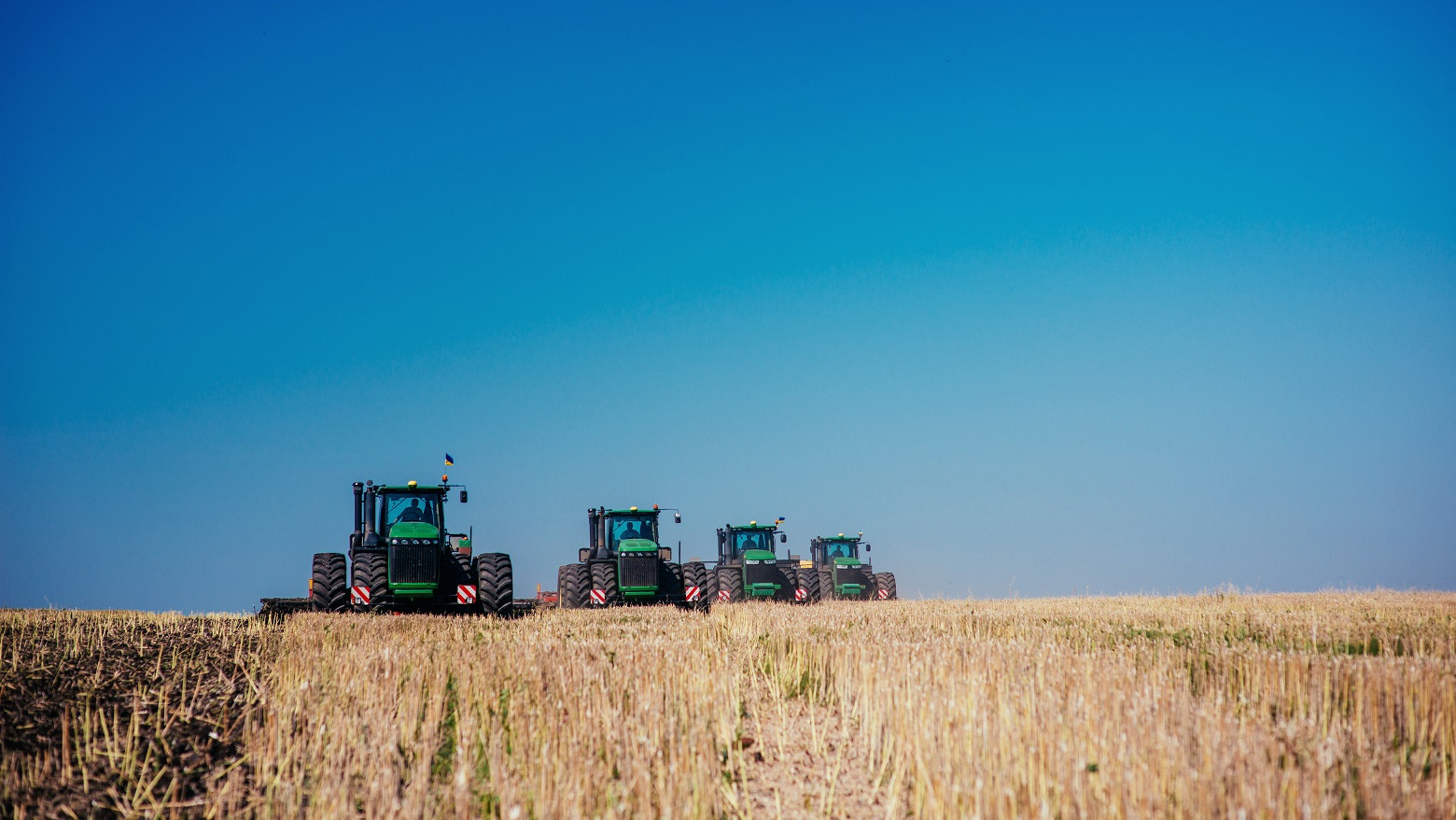 Fire traktorer er ved at høste en mark